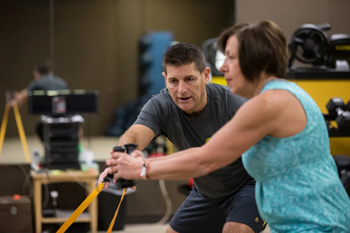 A YES Fitness coach guiding a member through an anti-rotation lateral drag with a resistance band